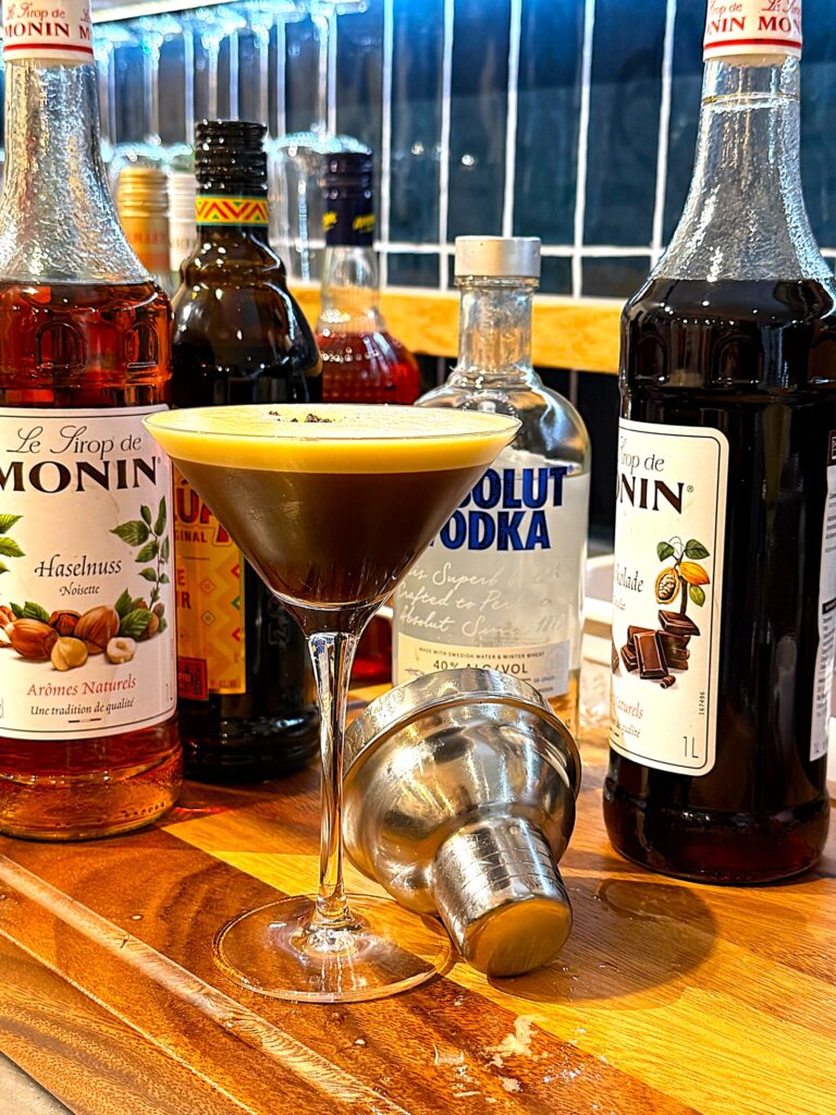 The Brown Cocktail auf dem Tresen mit Flaschen im Hintergrund